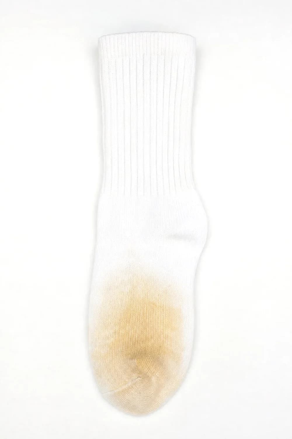 A white ribbed crew sock laid flat. Toe and ball only: the tone reads warm, towards yellow.