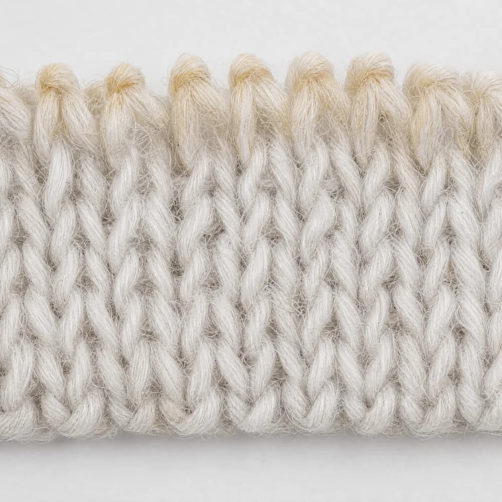 Extreme macro of white knitted cotton loops with a warm amber film oxidised into the crowns of the yarn.