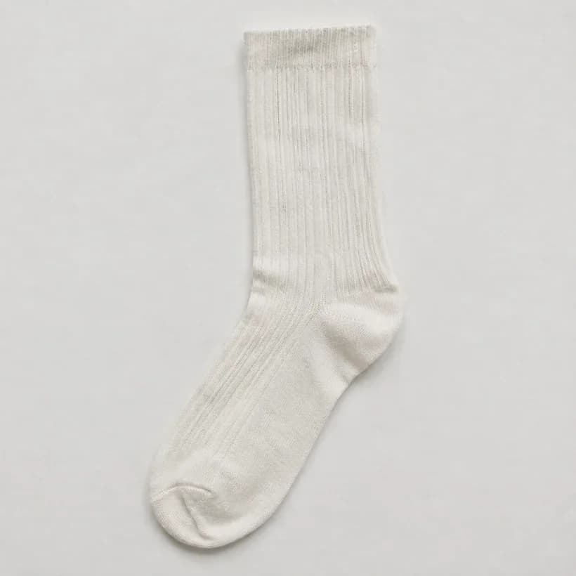 A white knee-length ribbed sock laid flat, dulled evenly along its whole length with no patch and no hue.