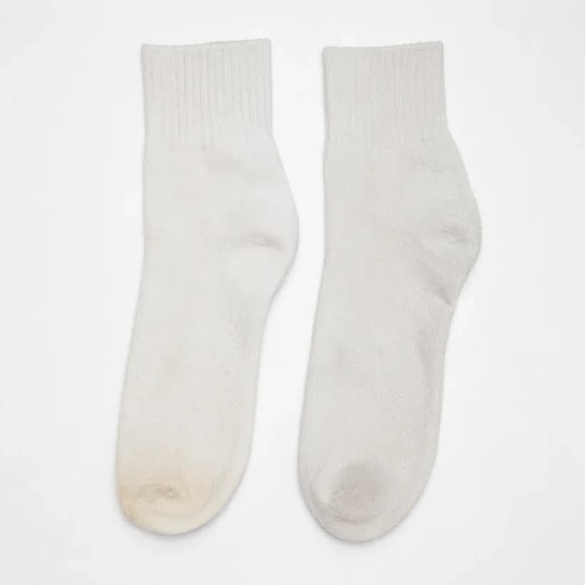 Two white socks of the same style laid side by side, one faintly warm at the toe and one evenly dulled overall.